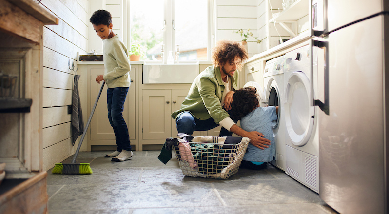 Man doing laundry and housework with his sons.